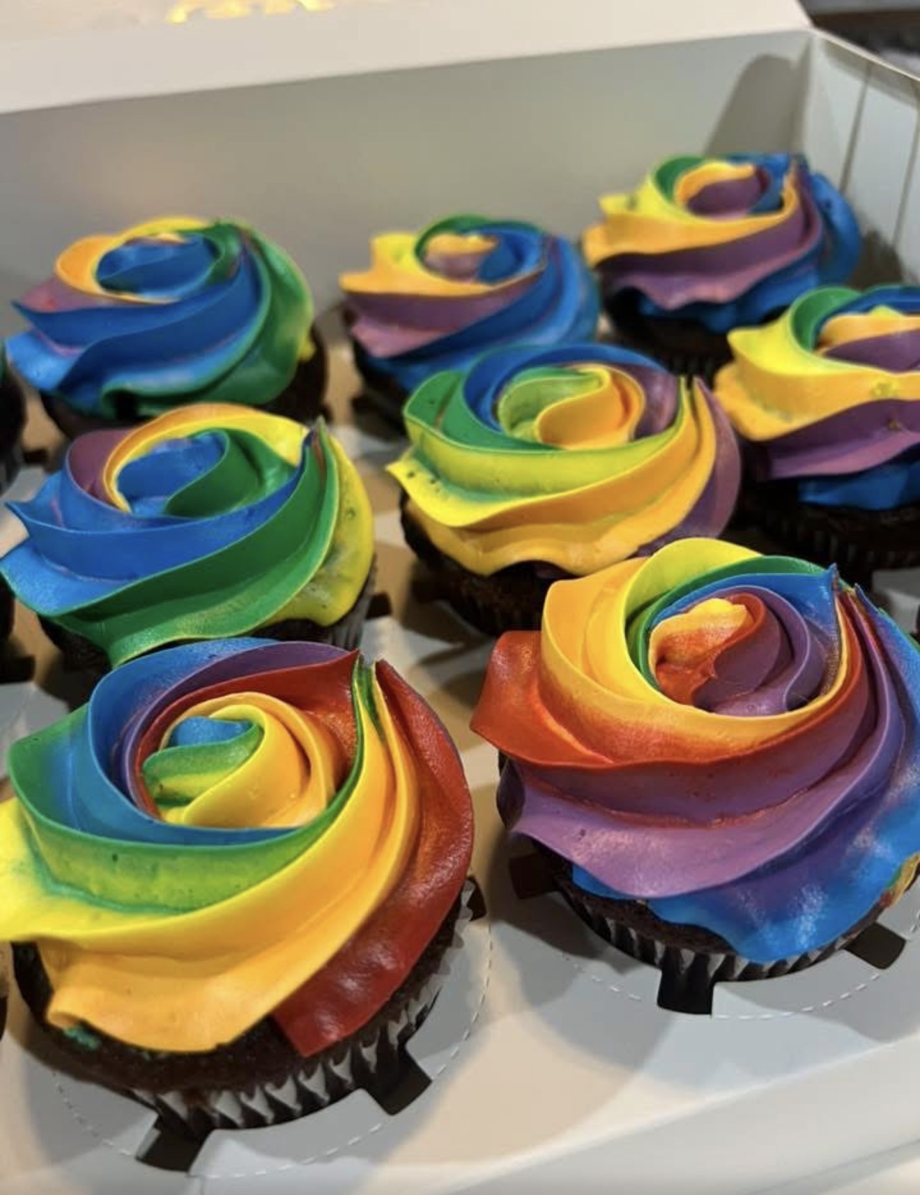 Chocolate cupcakes topped with rainbow buttercream swirls